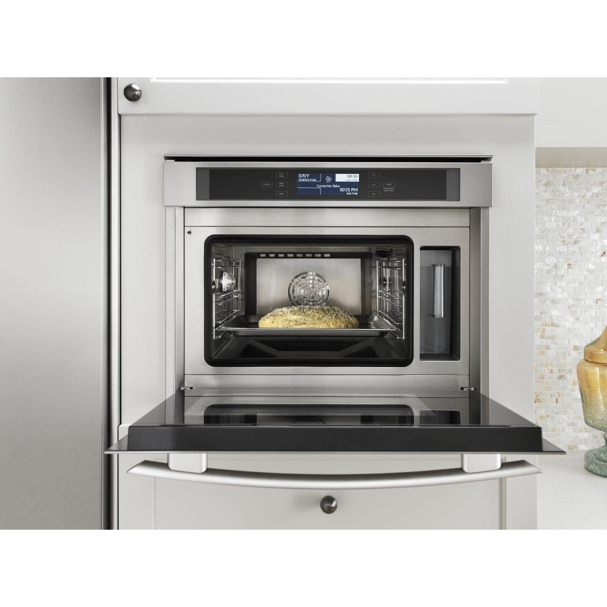 JennAir 24 inch built-in wall oven with the door open, showing the stainless oven cavity, rack guides, and a front water reservoir compartment