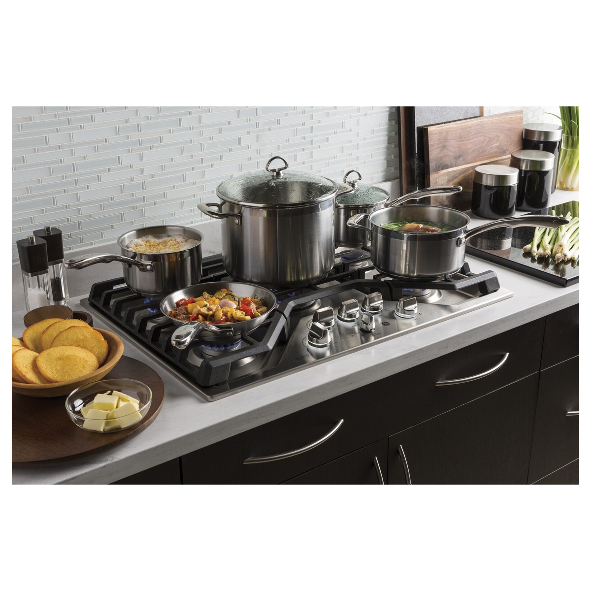 Café stainless gas cooktop installed in a kitchen countertop with multiple pots and pans cooking