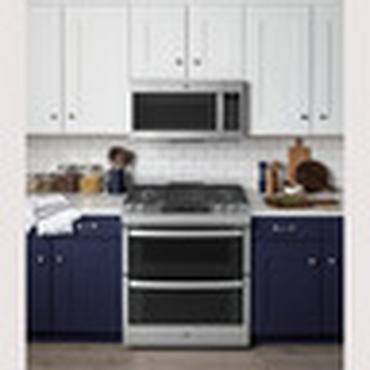 A stainless steel slide-in double oven range installed in a kitchen with cabinetry and a microwave above