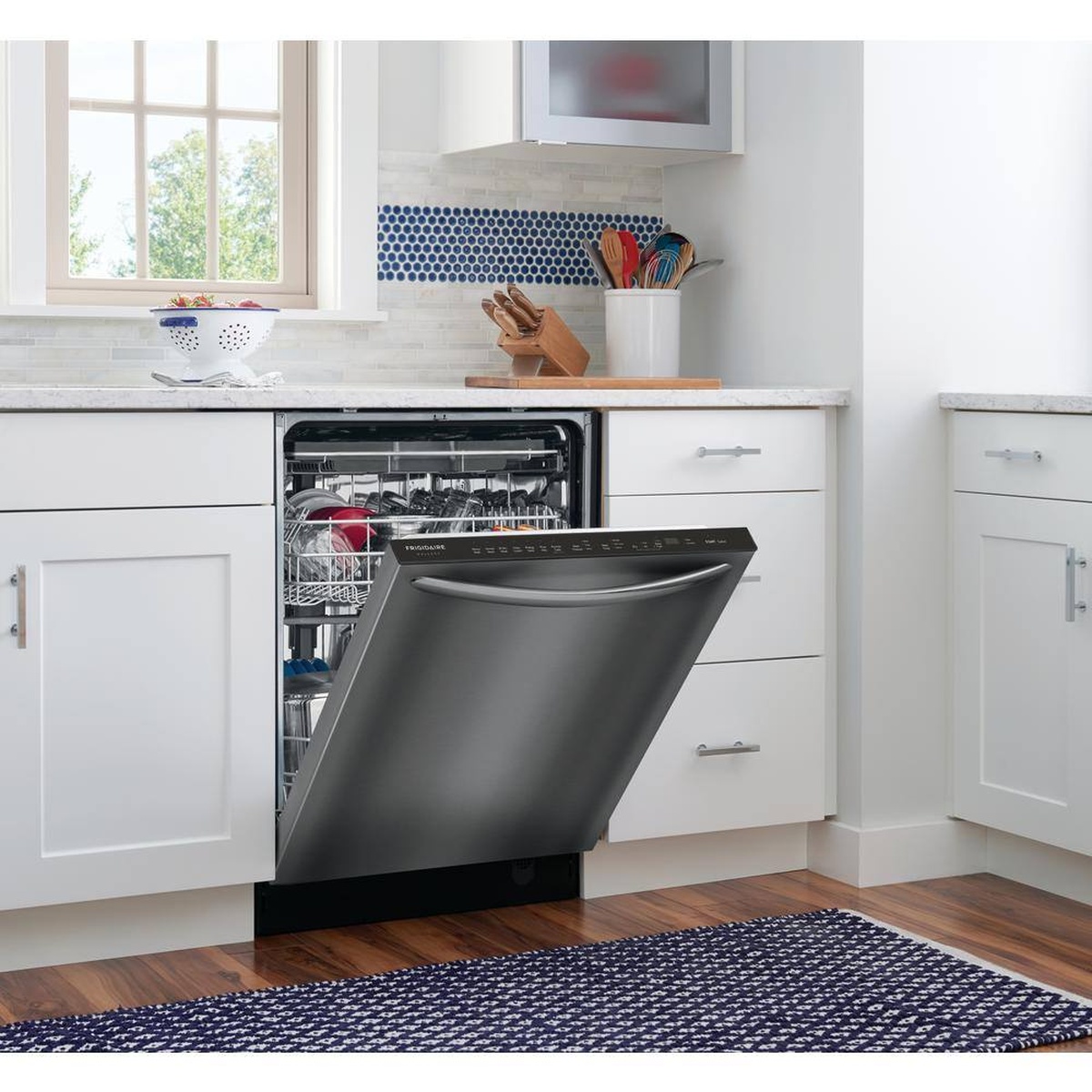 Built-in dishwasher installed under a white kitchen counter with the door partially open