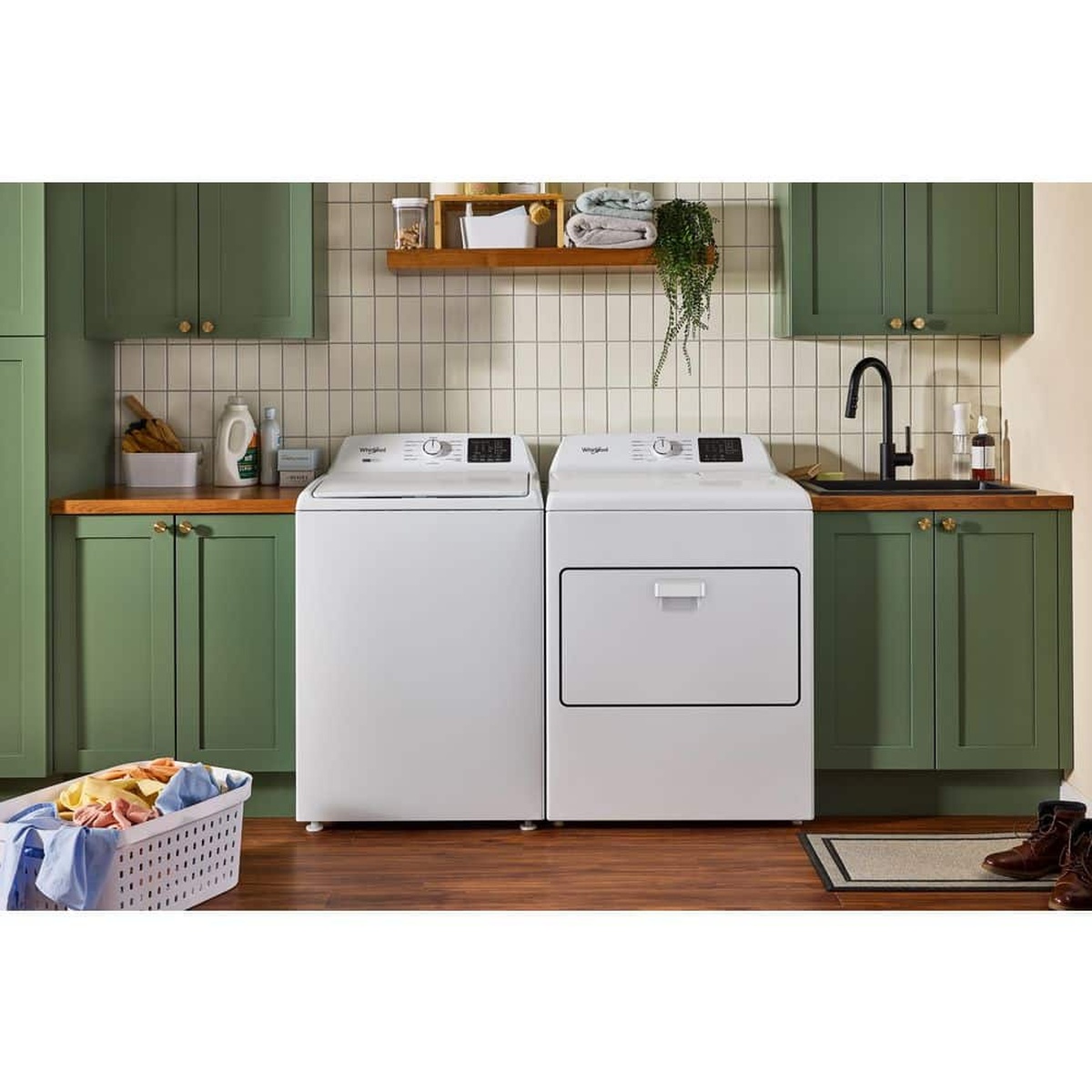Whirlpool washer and matching dryer installed side by side in a home laundry space with cabinets, sink, and laundry basket