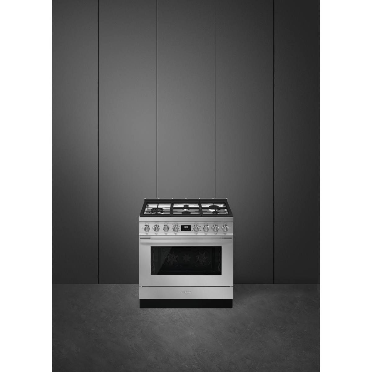 Stainless-steel Smeg freestanding gas range photographed in a minimal dark kitchen setting.
