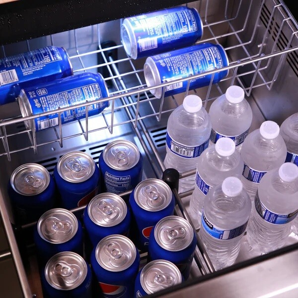 Inside view of a pull-out beverage drawer holding cans and bottled water in wire racks