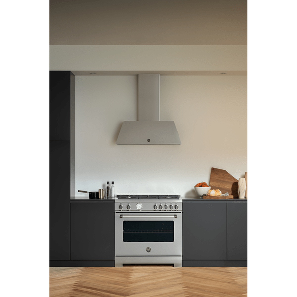 Bertazzoni range installed in a modern kitchen under a matching hood with dark cabinetry