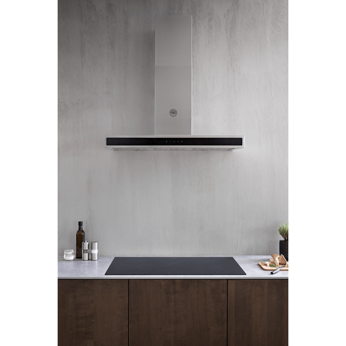 Minimal kitchen scene showing a slim black induction cooktop installed below a wall-mounted range hood
