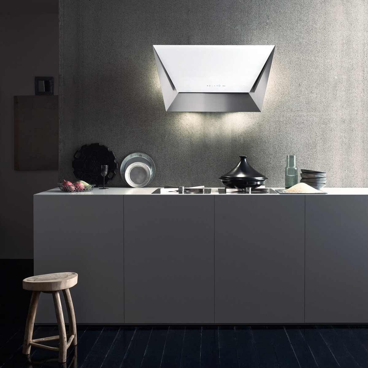 Modern wall-mounted Falmec Prisma Glass range hood with angled glass design and light glow above a cooktop