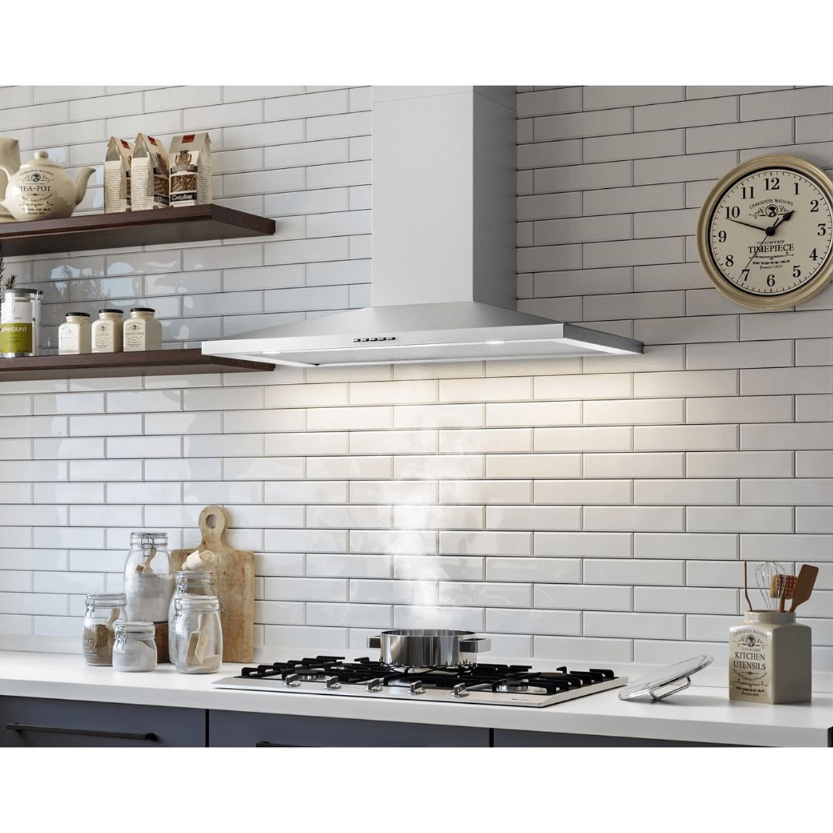 Stainless steel wall-mount range hood installed over a cooktop with the lights on