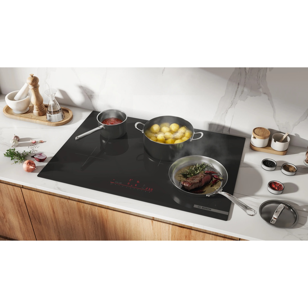 Bosch frameless black induction cooktop installed in a kitchen countertop with multiple pots and pans cooking