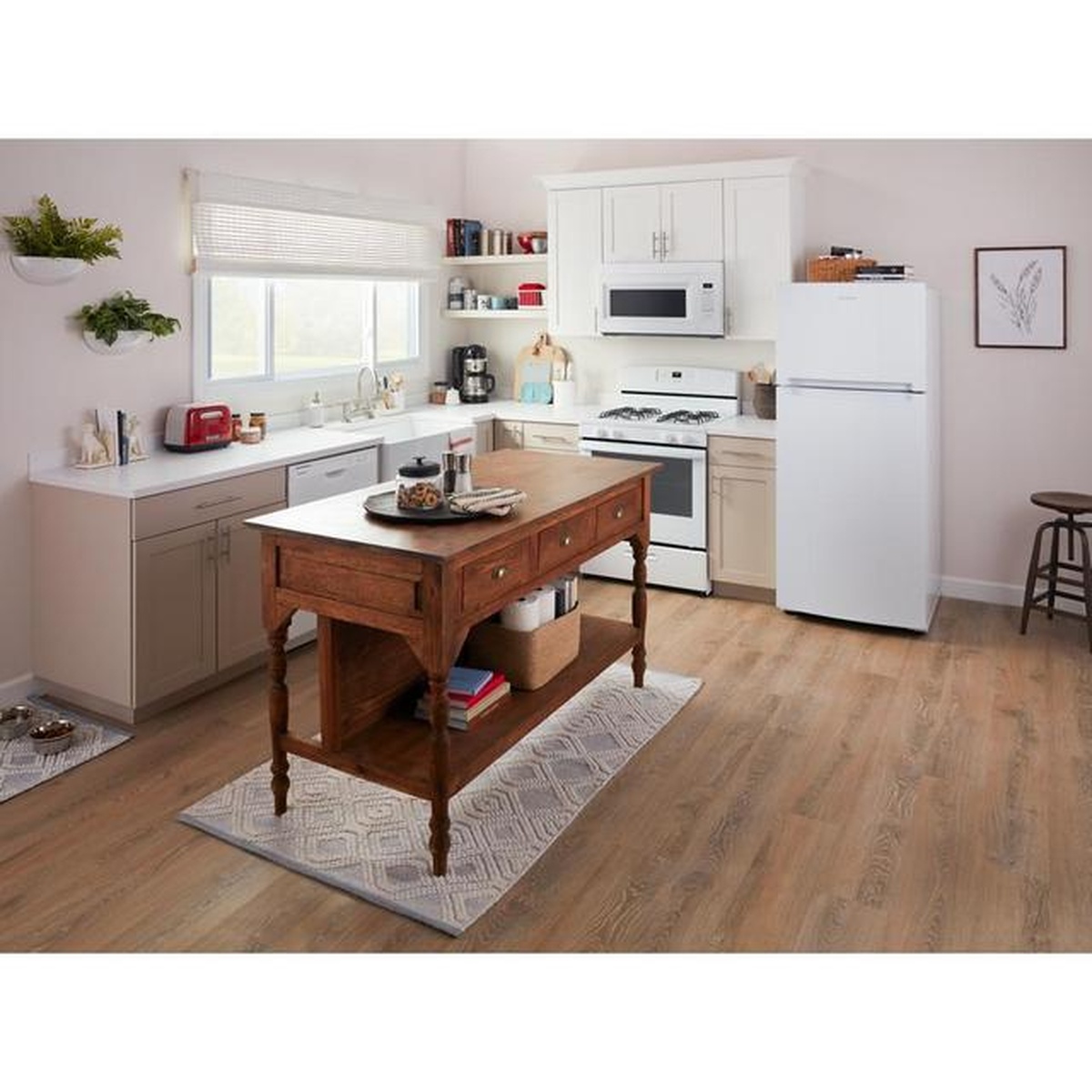 Amana top-freezer refrigerator in white installed in a bright, warm kitchen alongside a gas range and microwave