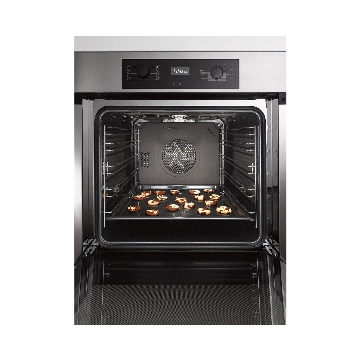 Miele H2265-1B oven door open showing spacious interior cavity with rear fan, adjustable wire rack, and cookies baking on the tray