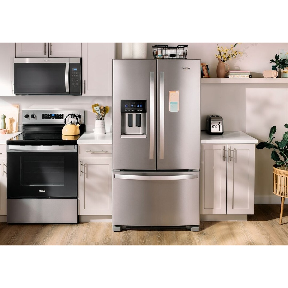 Whirlpool WRFF3436RZ stainless steel French door refrigerator installed in a modern white kitchen alongside matching Whirlpool range and over-the-range microwave