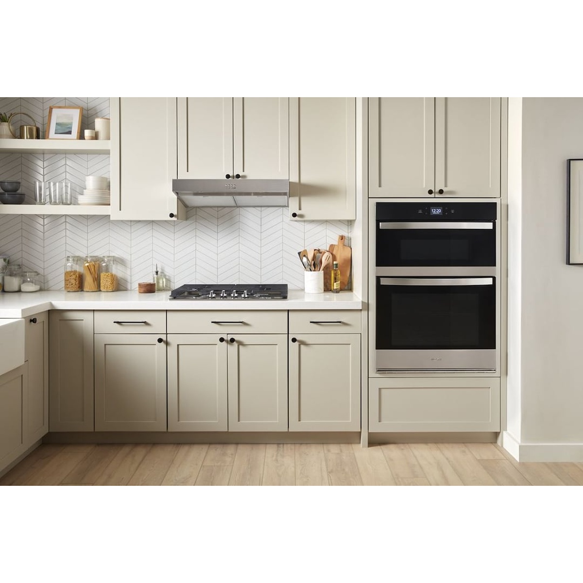 Whirlpool WOEC5027LZ combo wall oven installed flush in a cream-colored shaker kitchen cabinet beside a gas cooktop