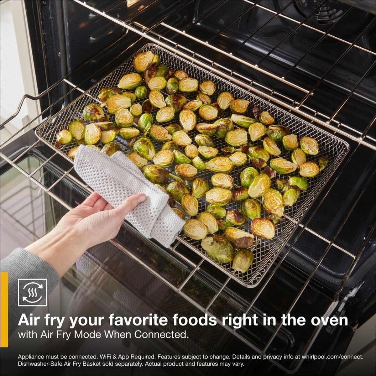 Air fry basket with roasted brussels sprouts being pulled from the wall oven rack, with on-screen text reading Air fry your favorite foods right in the oven with Air Fry Mode When Connected