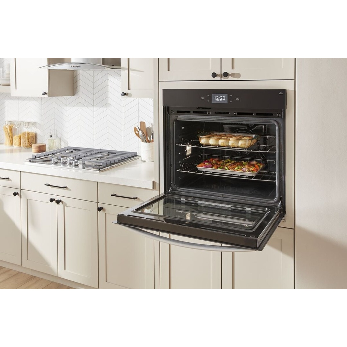 Whirlpool WOES7030PZ wall oven open in a bright kitchen with two racks loaded with food, showing oven interior capacity and rack positions