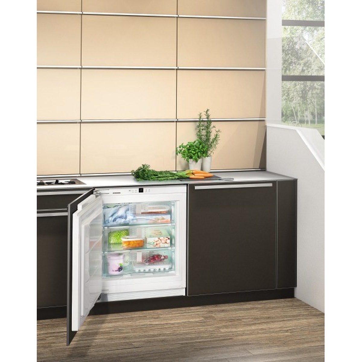 Liebherr UF501 installed under a kitchen counter in a modern kitchen with the door open showing organized frozen storage