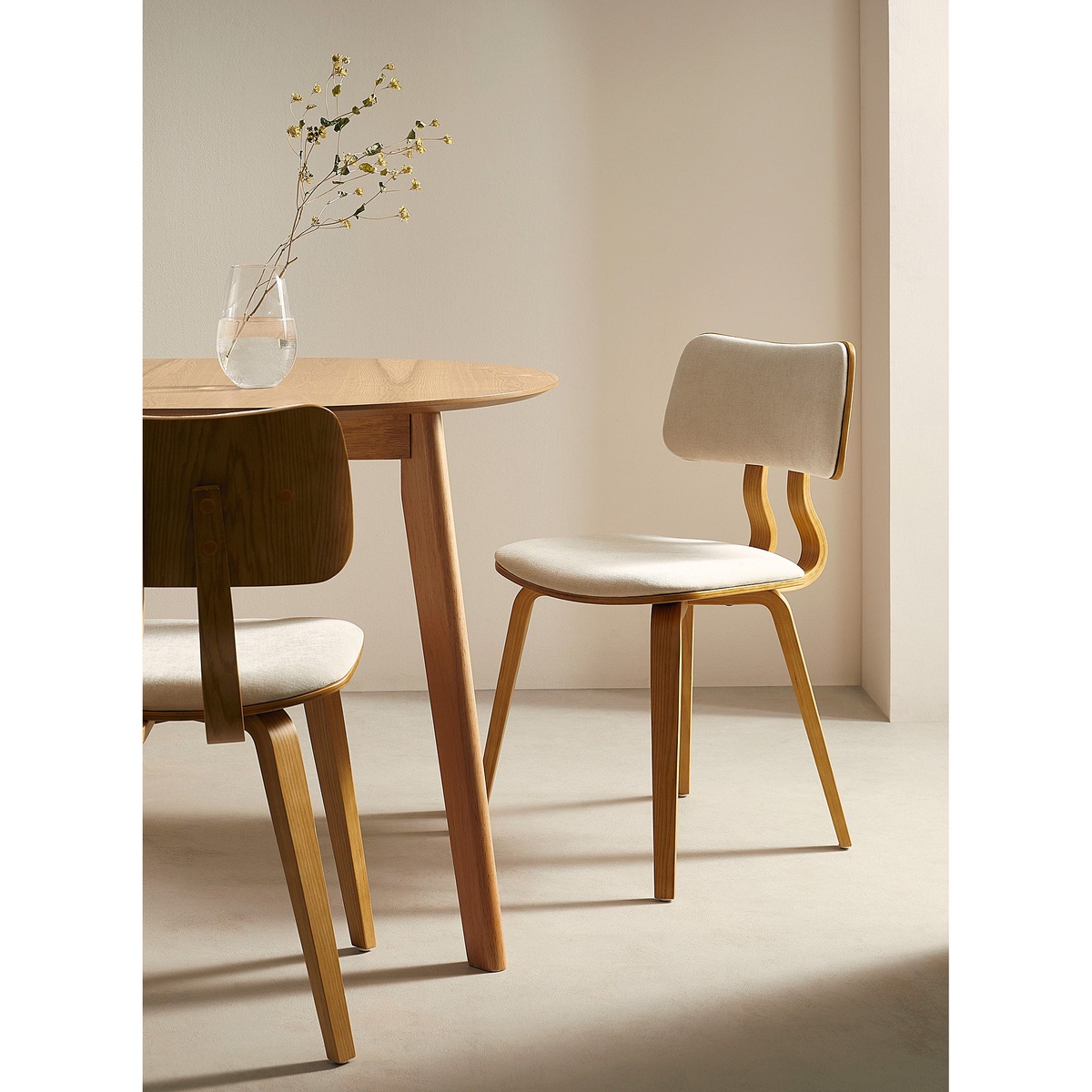Beige and natural wood dining chair styled beside a round wooden dining table