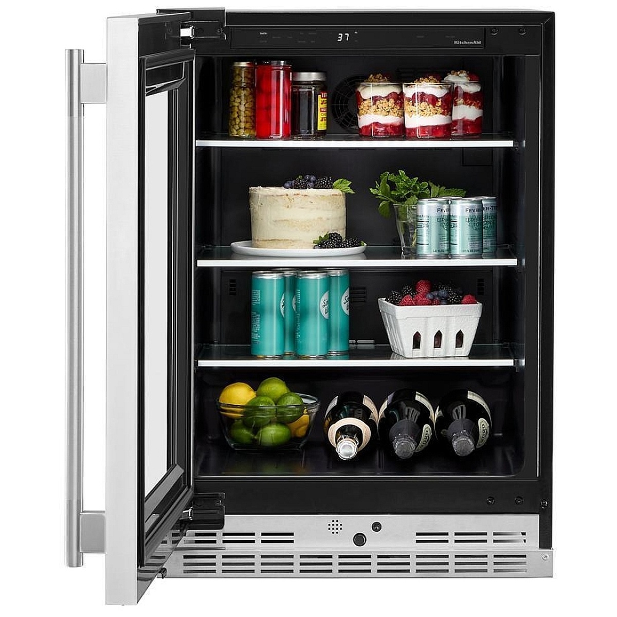 KitchenAid KURL524SPS interior open view showing three glass shelves loaded with canned beverages, bottles, a cake, fruit and jars, with backlit touch controls visible at the top