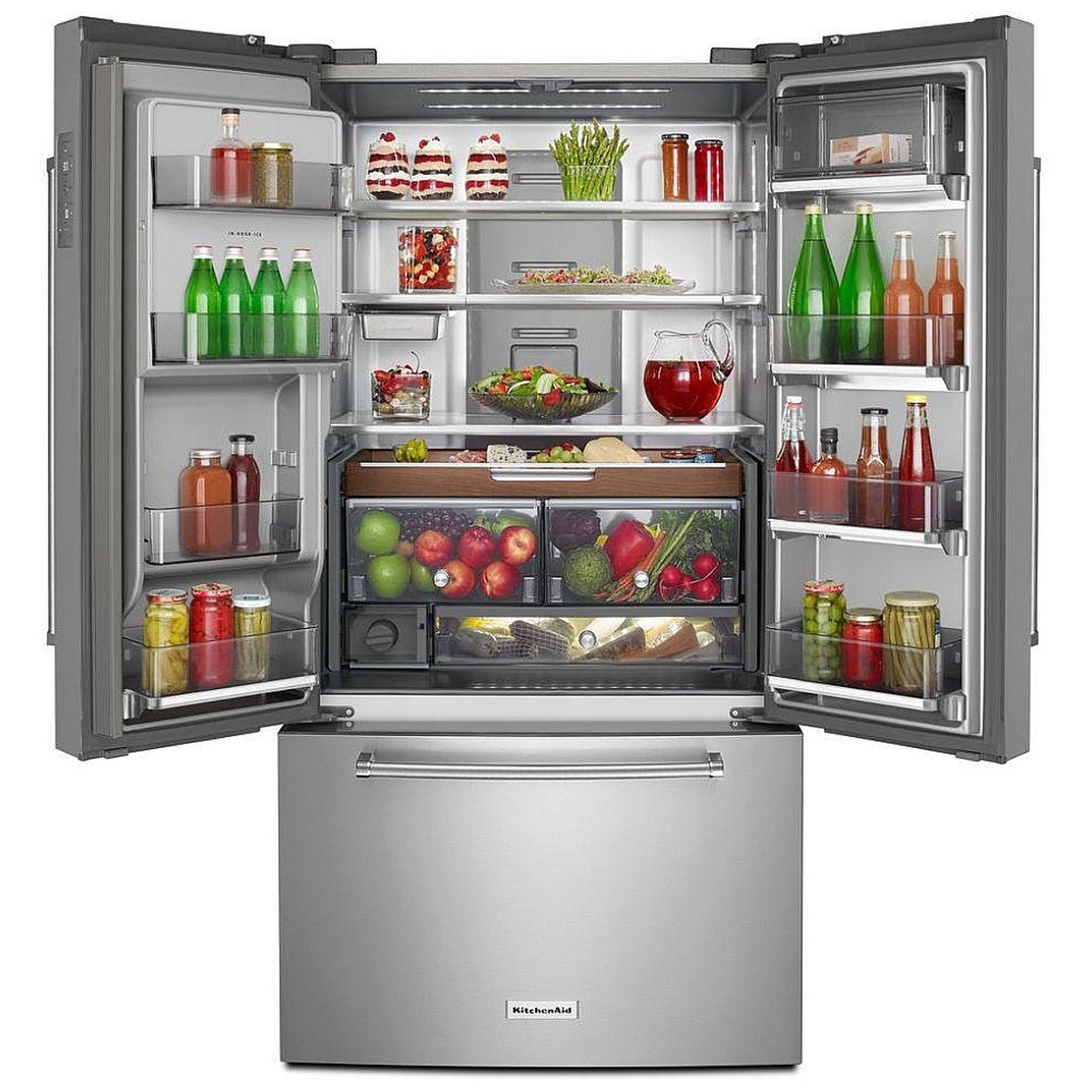 Open KitchenAid French door refrigerator showing adjustable shelves, door bins, wood-finish pull-out tray, and full-width pantry drawer
