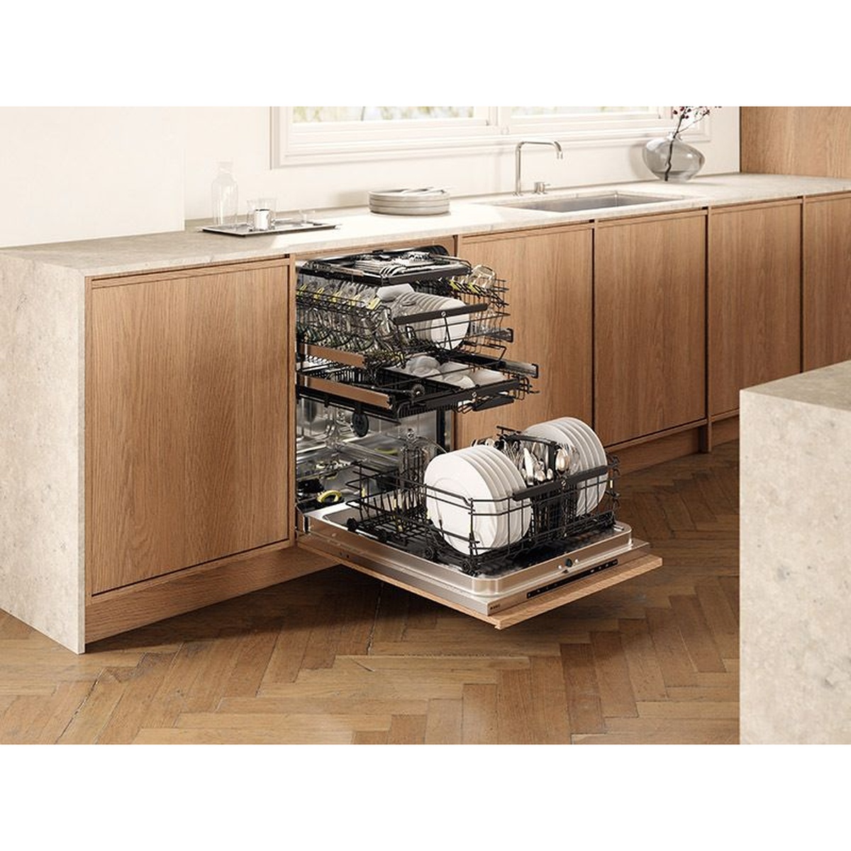 Built-in dishwasher installed in a modern kitchen with the door open and multiple racks pulled out, loaded with plates and cookware.