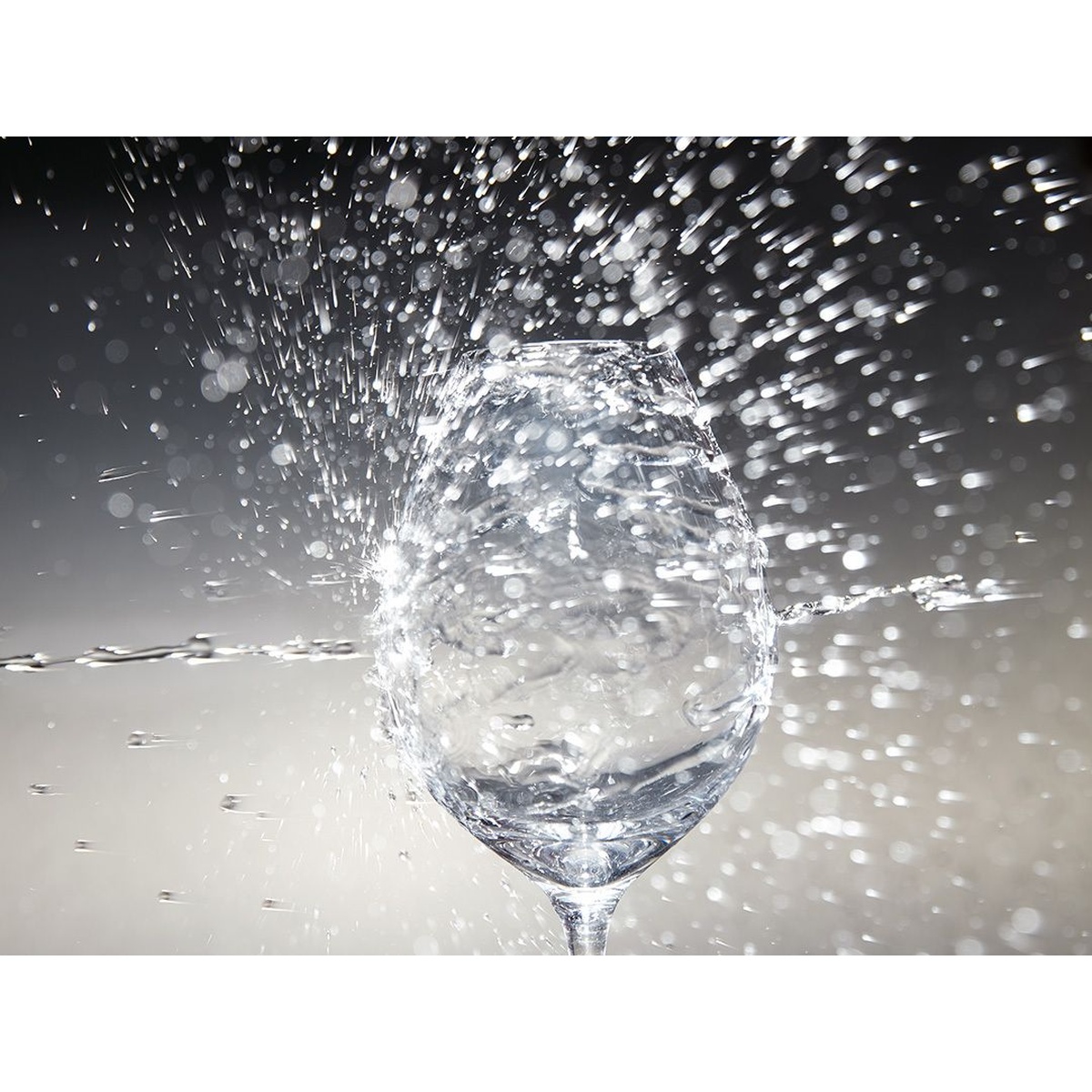High-speed water splashing through a crystal wine glass, showcasing the powerful and precise cleaning performance of the ASKO dishwasher