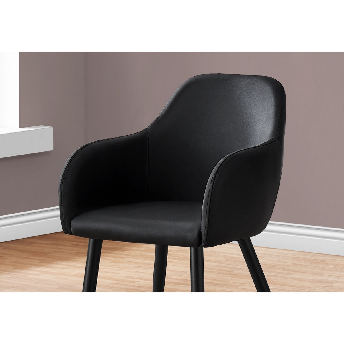 Close-up of the black leather-look upholstery, padded back, and integrated armrest of the Amara dining chair in a room setting