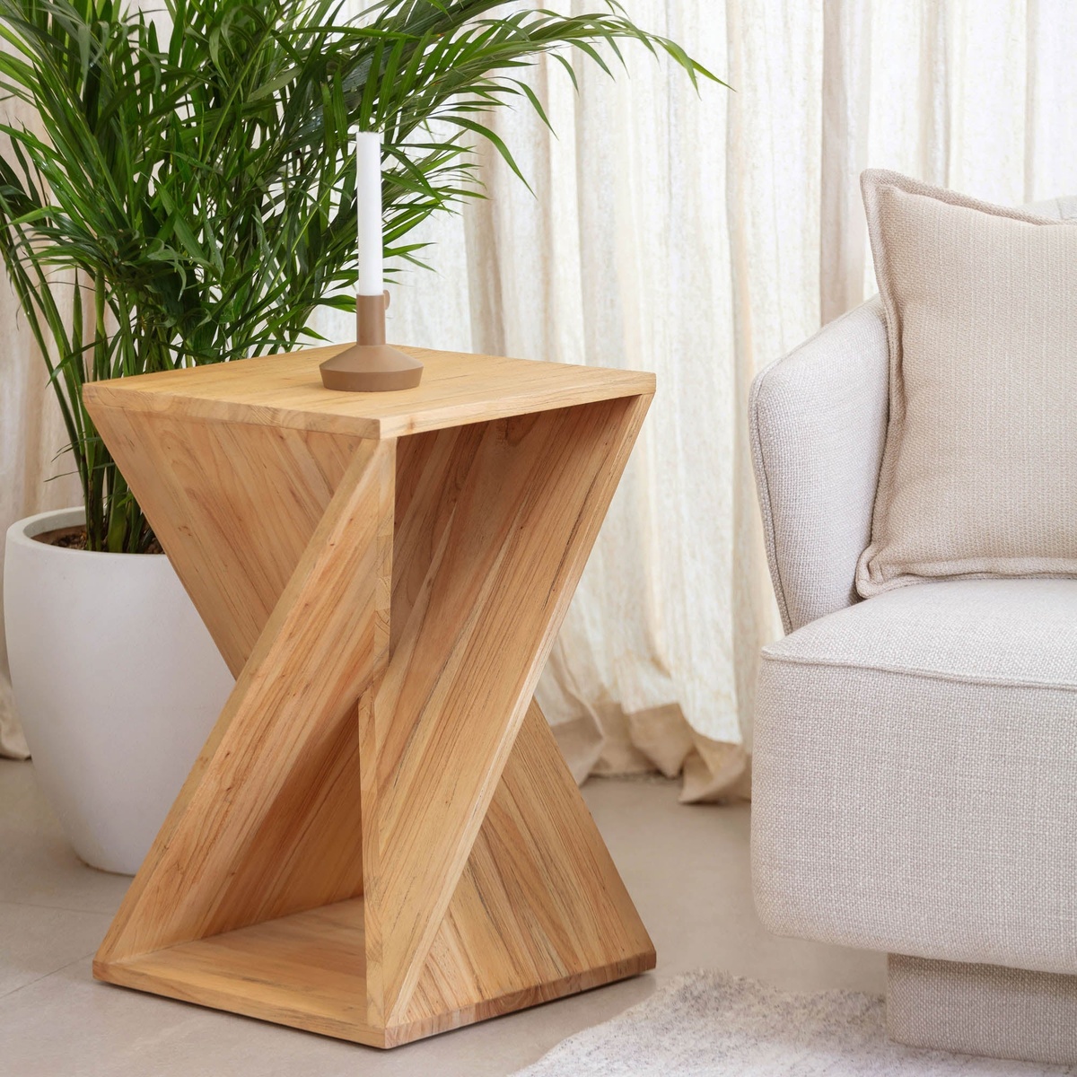 Silhouette Side Table styled next to a cream sofa with a candle holder on top and a large potted palm plant in the background