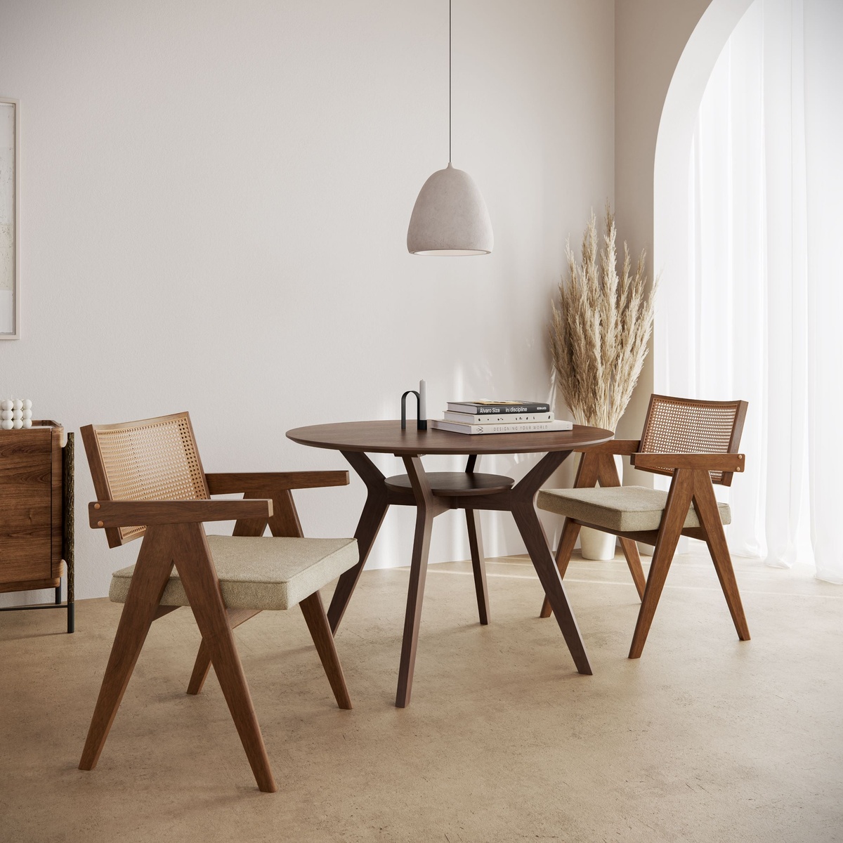 Ansel Dining Table in walnut finish styled in a bright dining room with two rattan-back chairs, pampas grass, and a pendant light