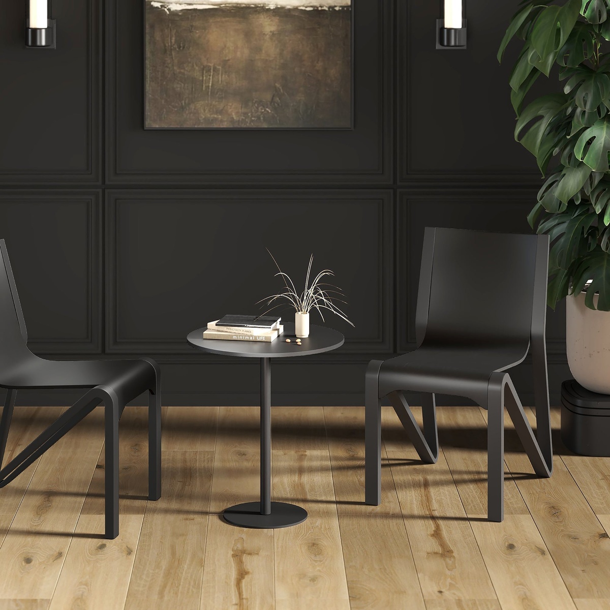 Two Soren black stackable wood dining chairs flanking a small round black table in a dark, modern dining space with wood floors and a tropical plant