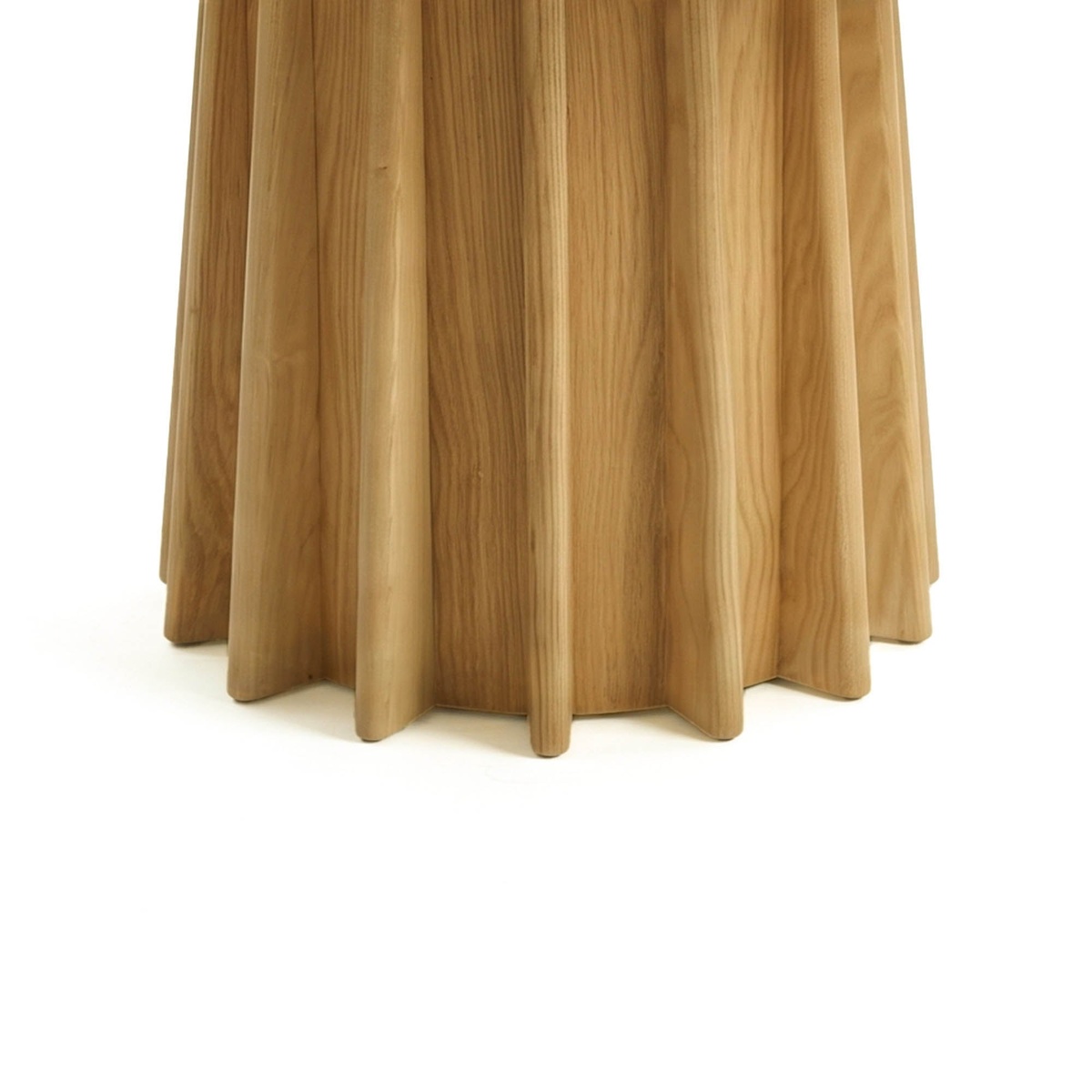 Close-up detail of the Sculpture Dining Table's fluted oak pedestal base showing sculpted vertical ribs and natural wood grain