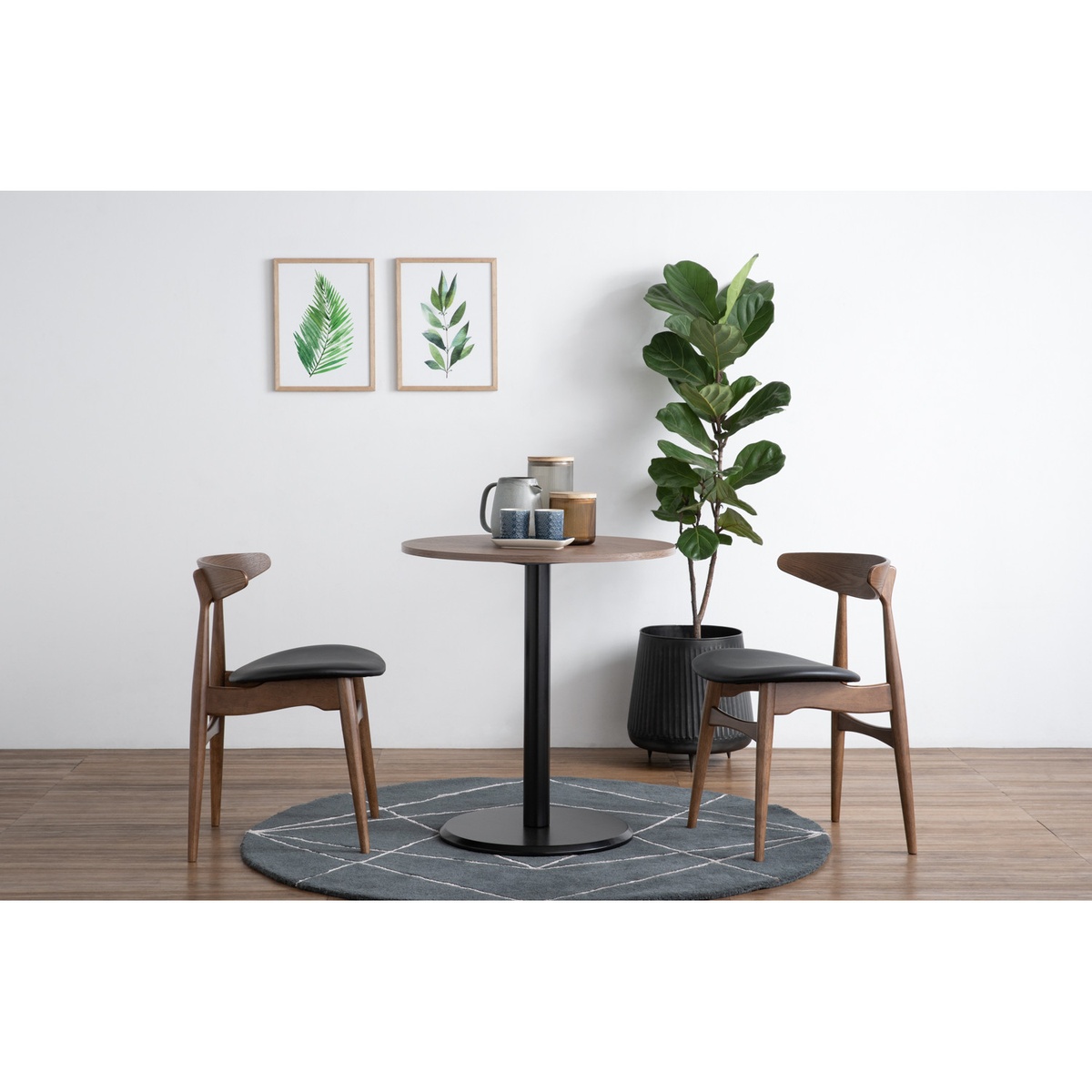 Two Tricia Dining Chairs 109/530 styled around a round pedestal dining table in a modern living space with warm wood floors and greenery