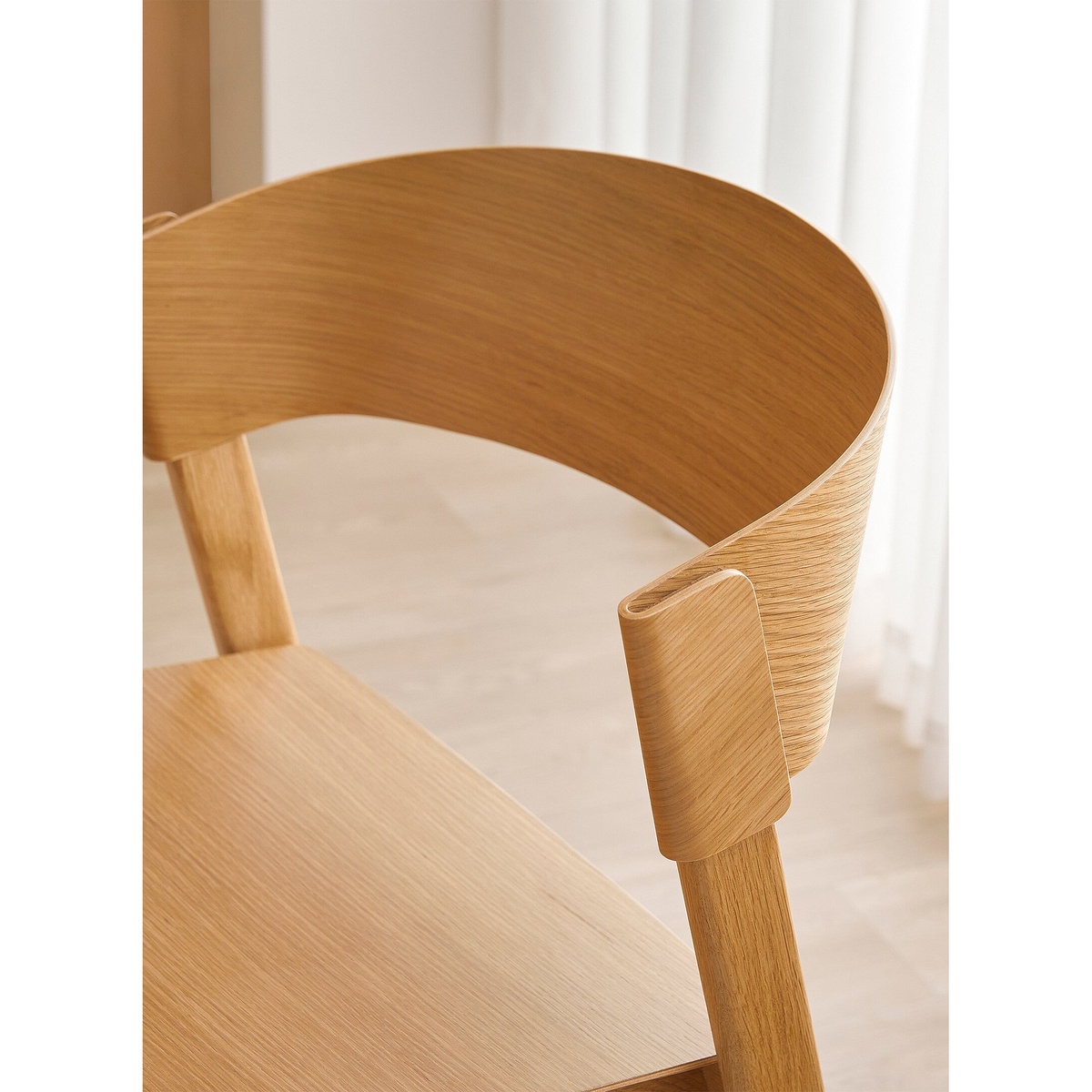 Close-up detail of the Aldo Dining Chair's curved oak veneer back and solid wood joinery connection