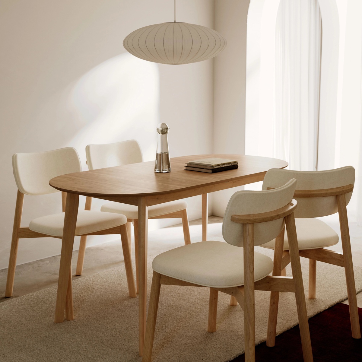 Dining table styled with four matching beige and oak dining chairs in a softly lit dining room