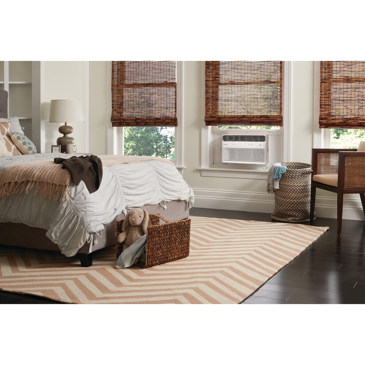 Frigidaire FHWW084WD1 window air conditioner installed in a bedroom window above a neatly made bed in a bright, well-furnished room