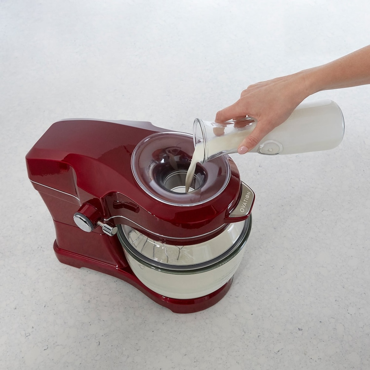 Top view of a red Kenmore Elite Ovation stand mixer as milk is poured into the pour-in opening while mixing