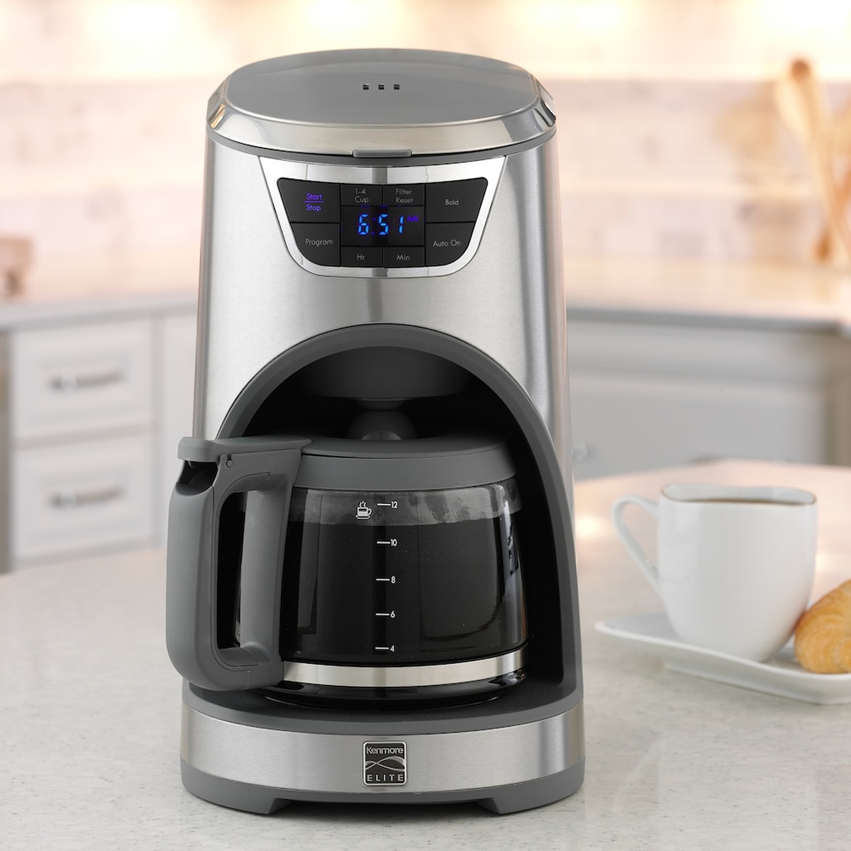 Kenmore Elite stainless steel 12-cup coffee maker on a kitchen counter with blue digital display and glass carafe