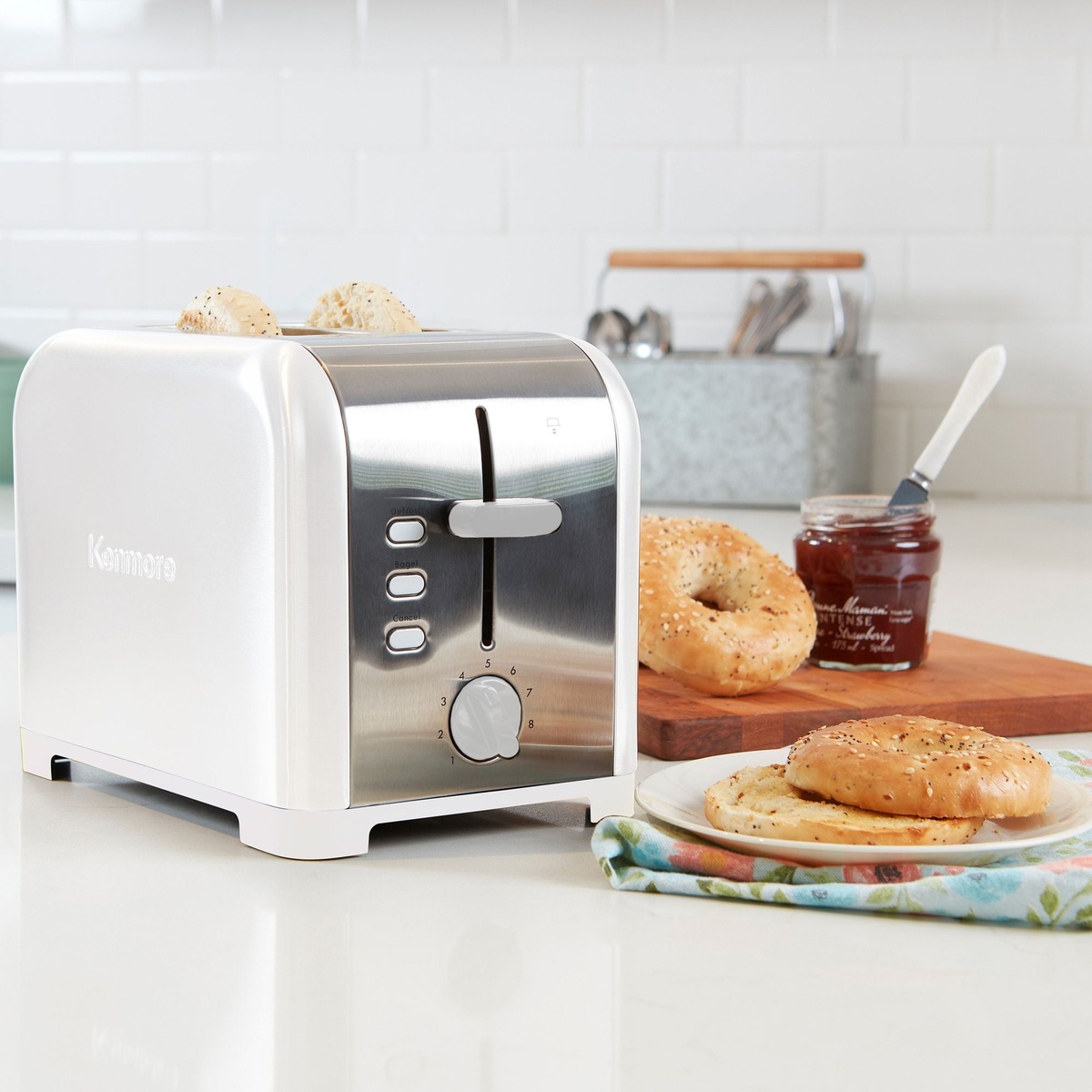 White and stainless Kenmore 2-slice toaster on a kitchen counter beside bagels