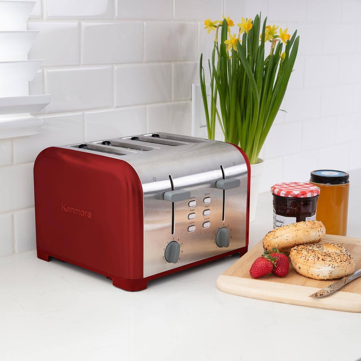 Kenmore red and stainless steel 4-slice toaster on a kitchen counter near bagels and jam