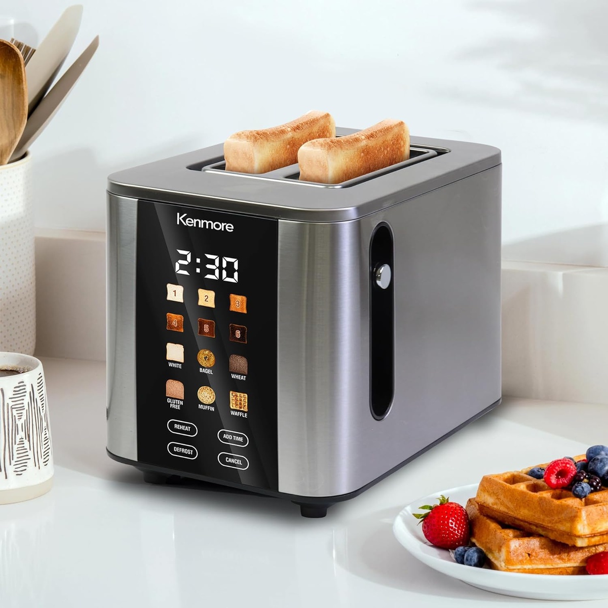 Kenmore stainless steel touchscreen toaster on a kitchen counter beside a plate of waffles