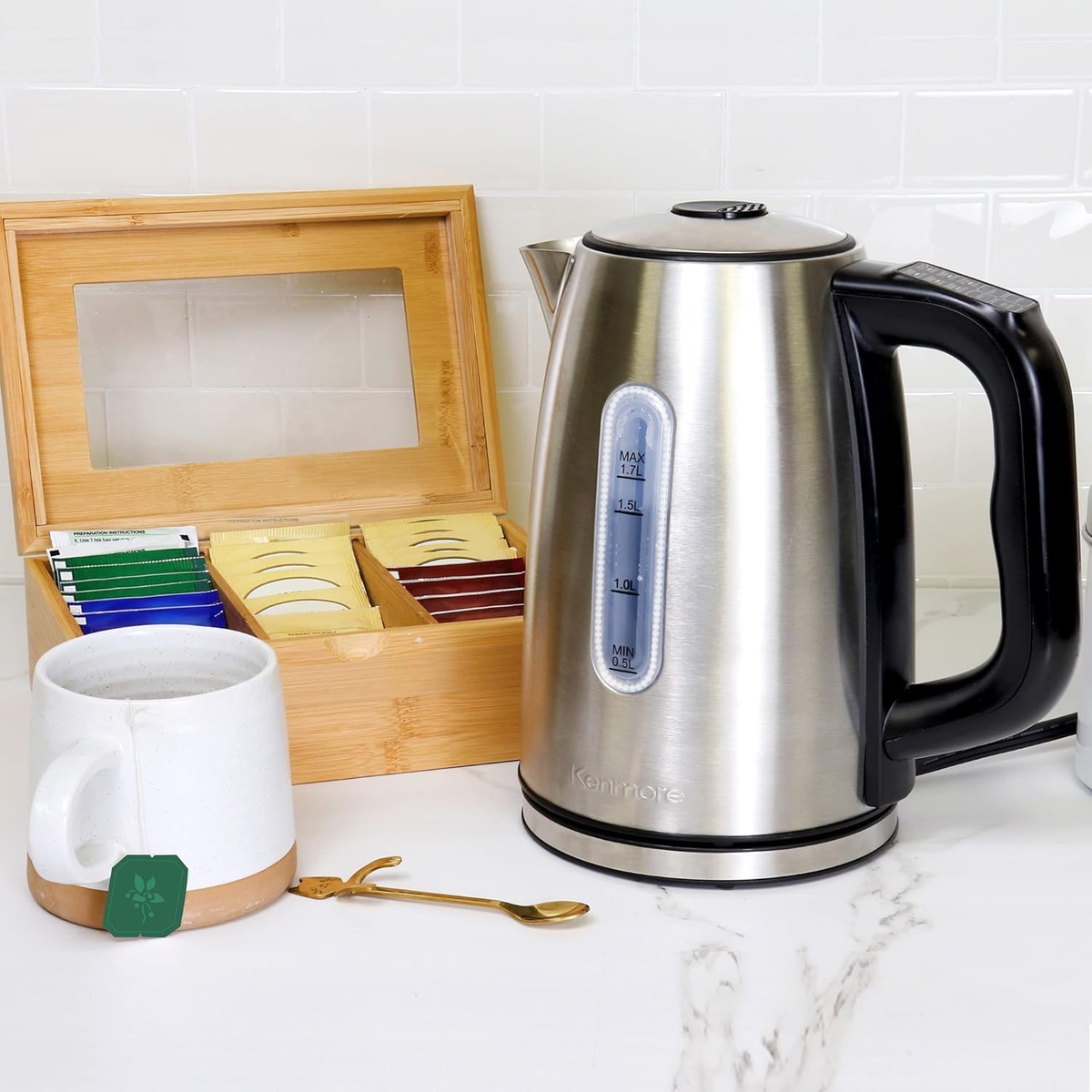 Stainless steel Kenmore electric kettle on a kitchen counter beside a tea box and mug