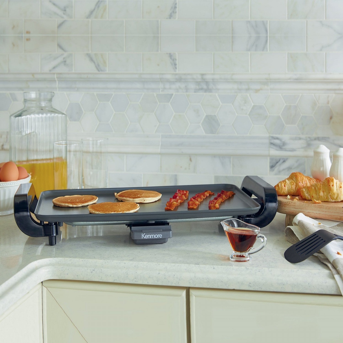 Kenmore electric griddle on a kitchen counter cooking pancakes and bacon