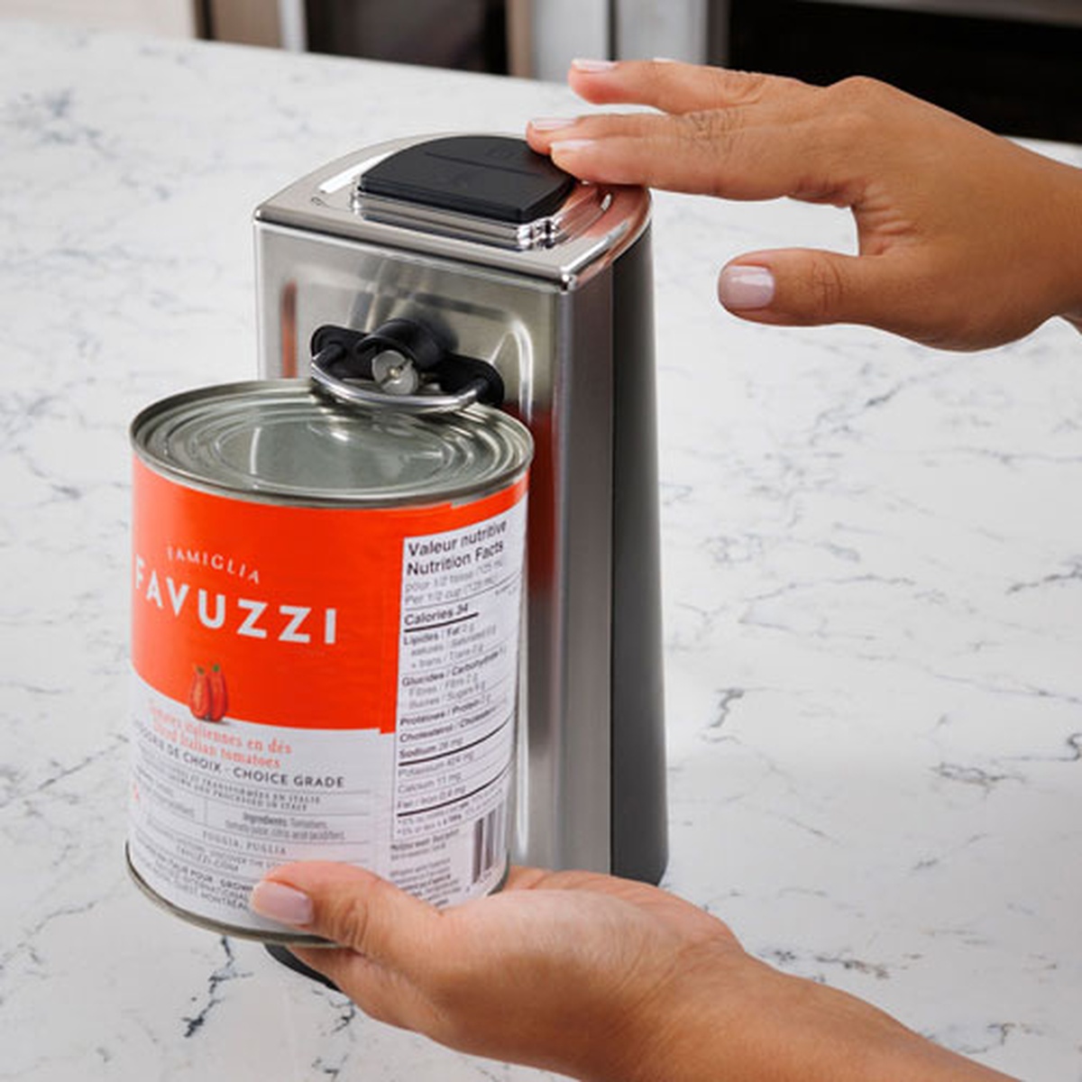 Hand pressing the top button on the Kenmore electric can opener while it holds a large can