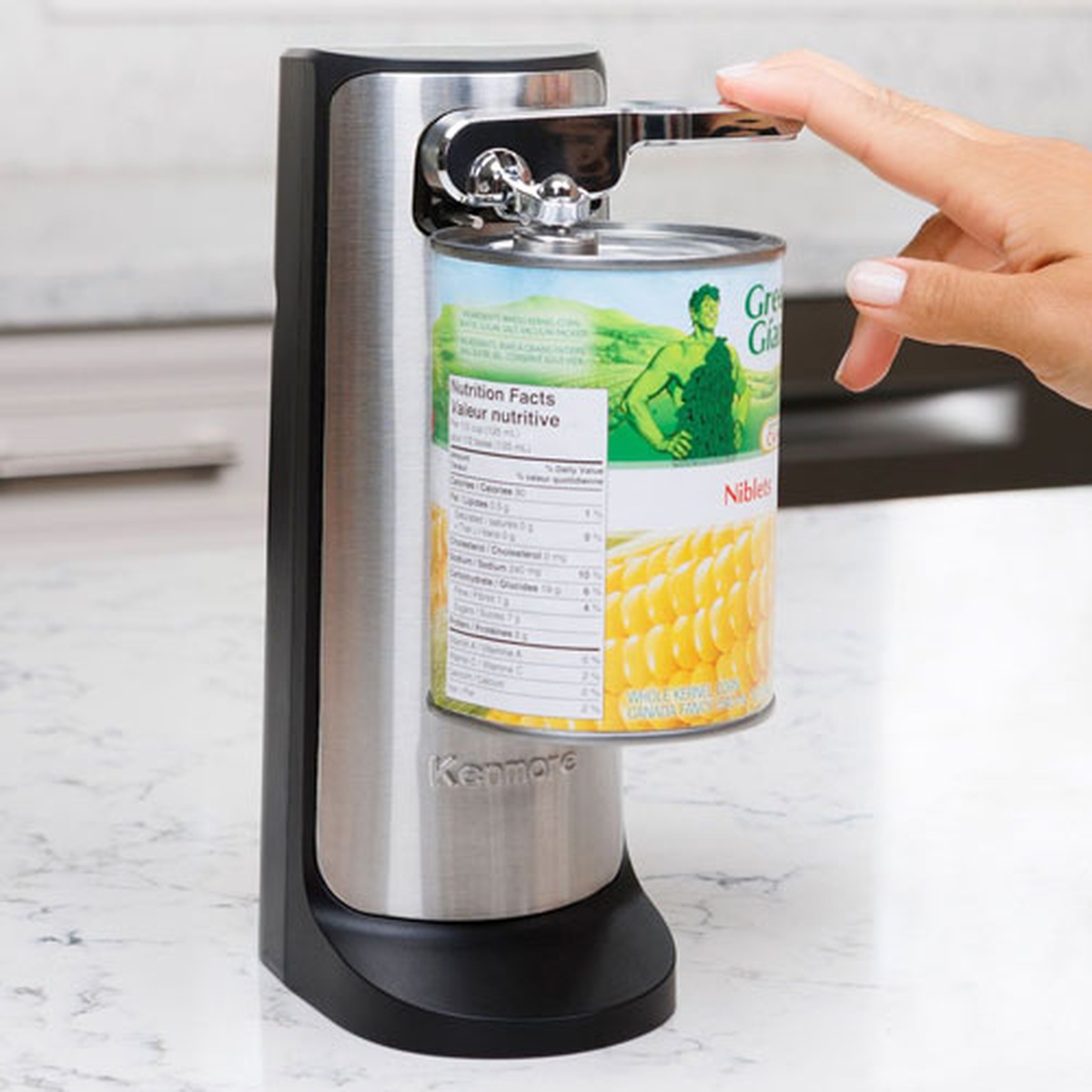 Kenmore electric can opener operating on a can with a hand pressing the lever