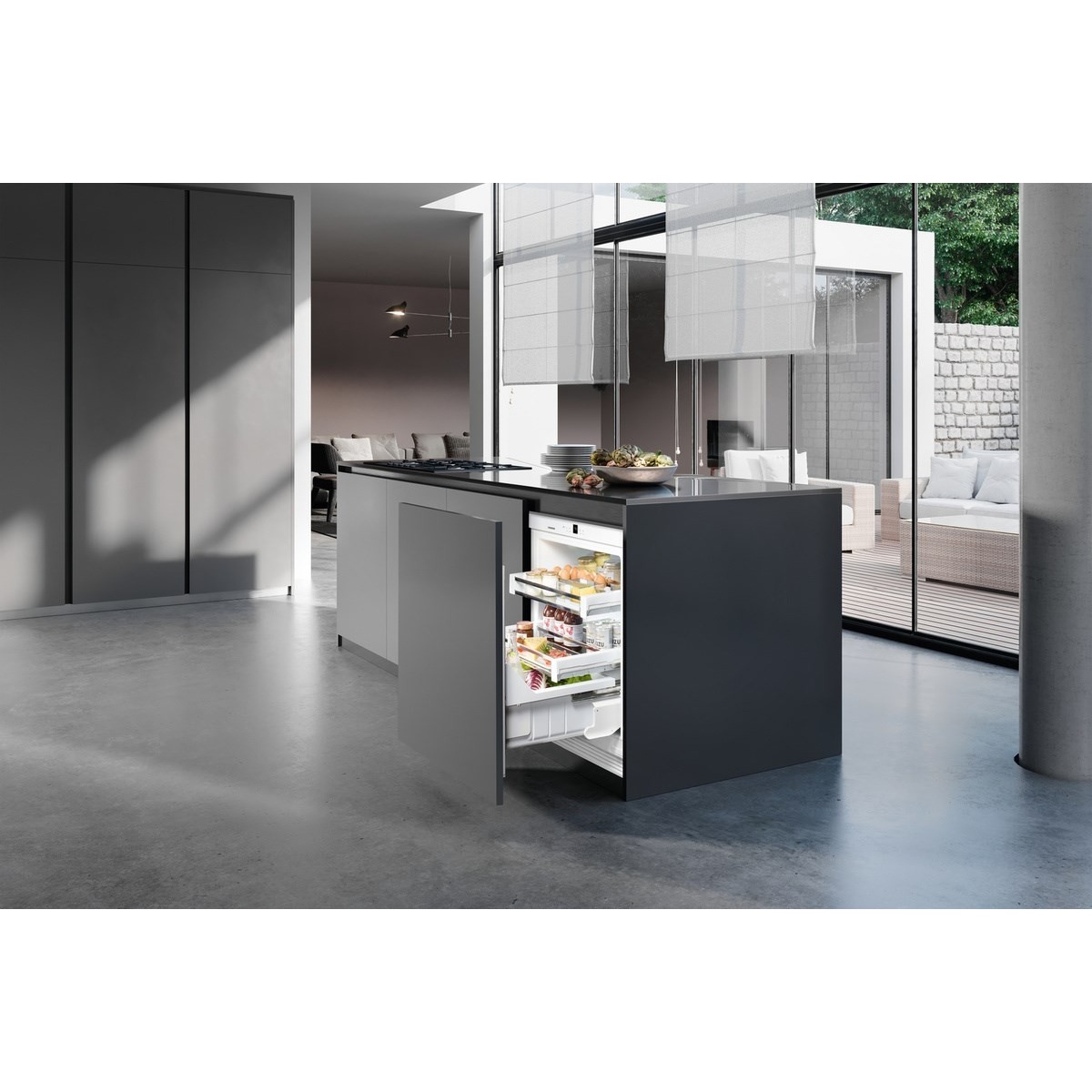 Liebherr UPR513 installed flush beneath a dark kitchen island in a modern open-plan space with the pull-out drawer open revealing organized food storage
