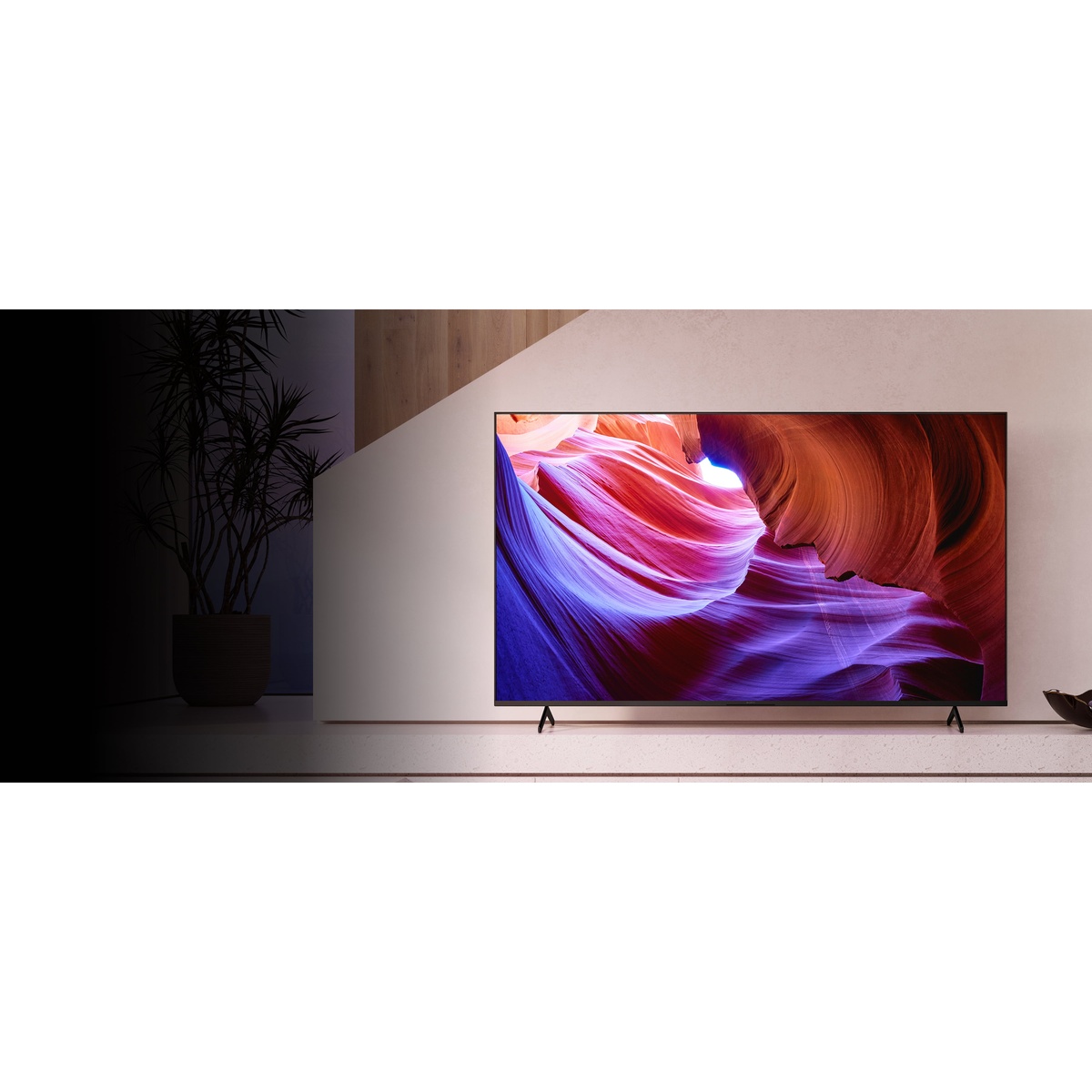 Sony X85K 65-inch TV displayed in a modern living room, showing vibrant red and blue canyon visuals on screen