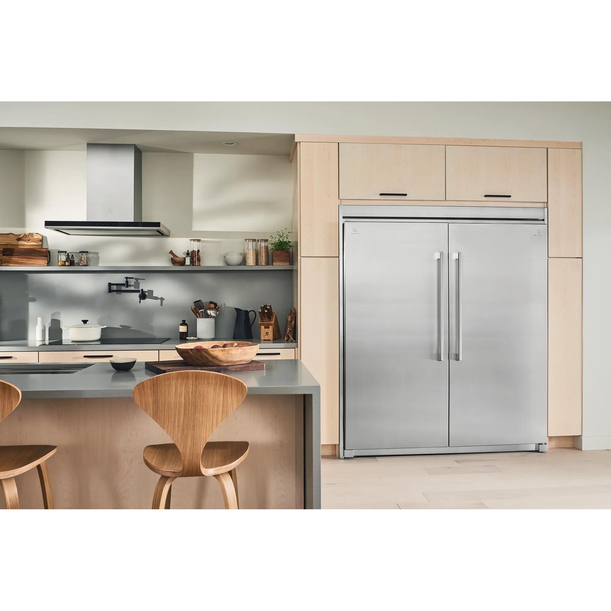Electrolux EI33AF80WS freezer and EI33AR80WS refrigerator paired side by side with trim kits in a modern kitchen with light wood cabinetry