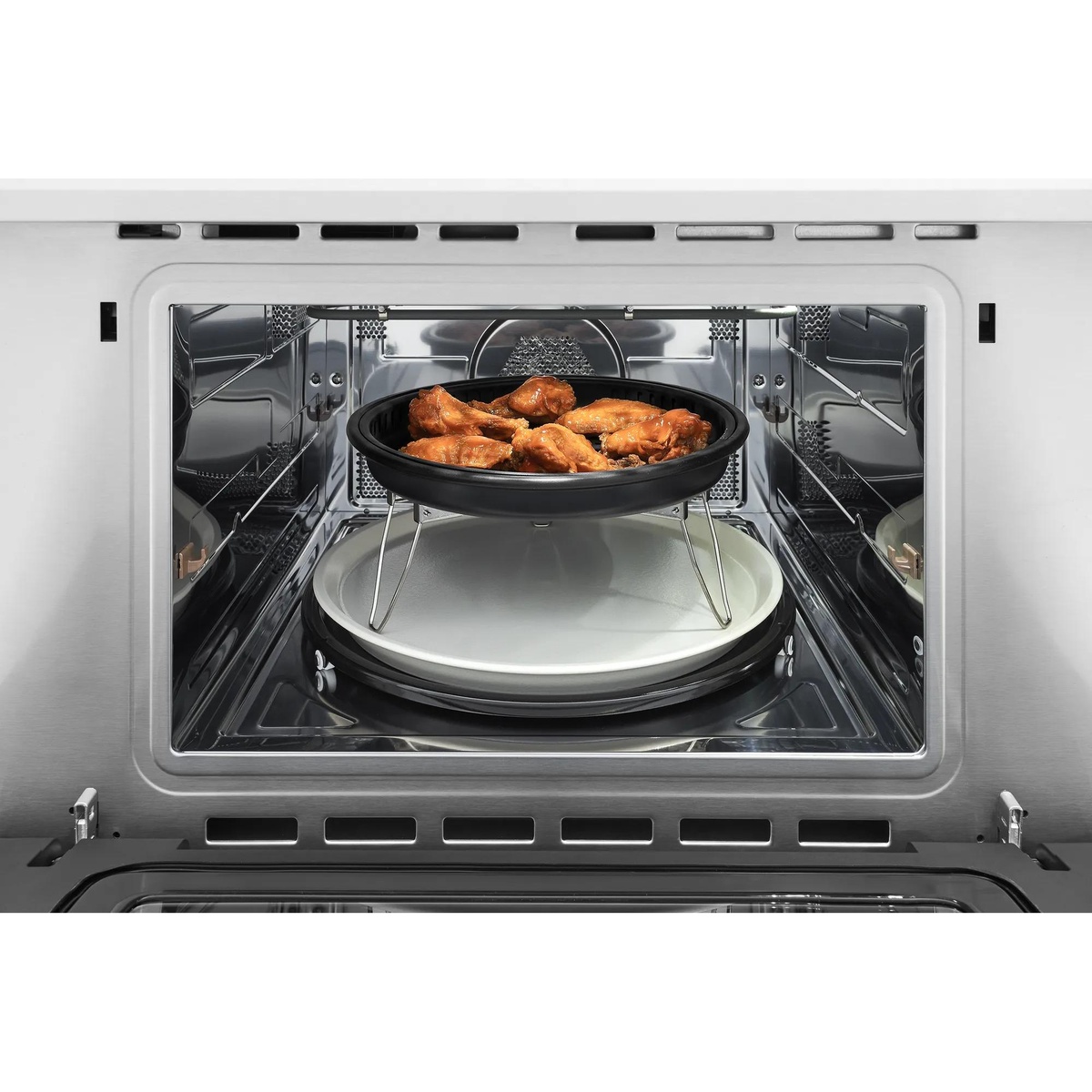 Frigidaire Professional built-in microwave interior showing air-fried chicken wings in the included ceramic Air Fry Pan elevated on the offset rack