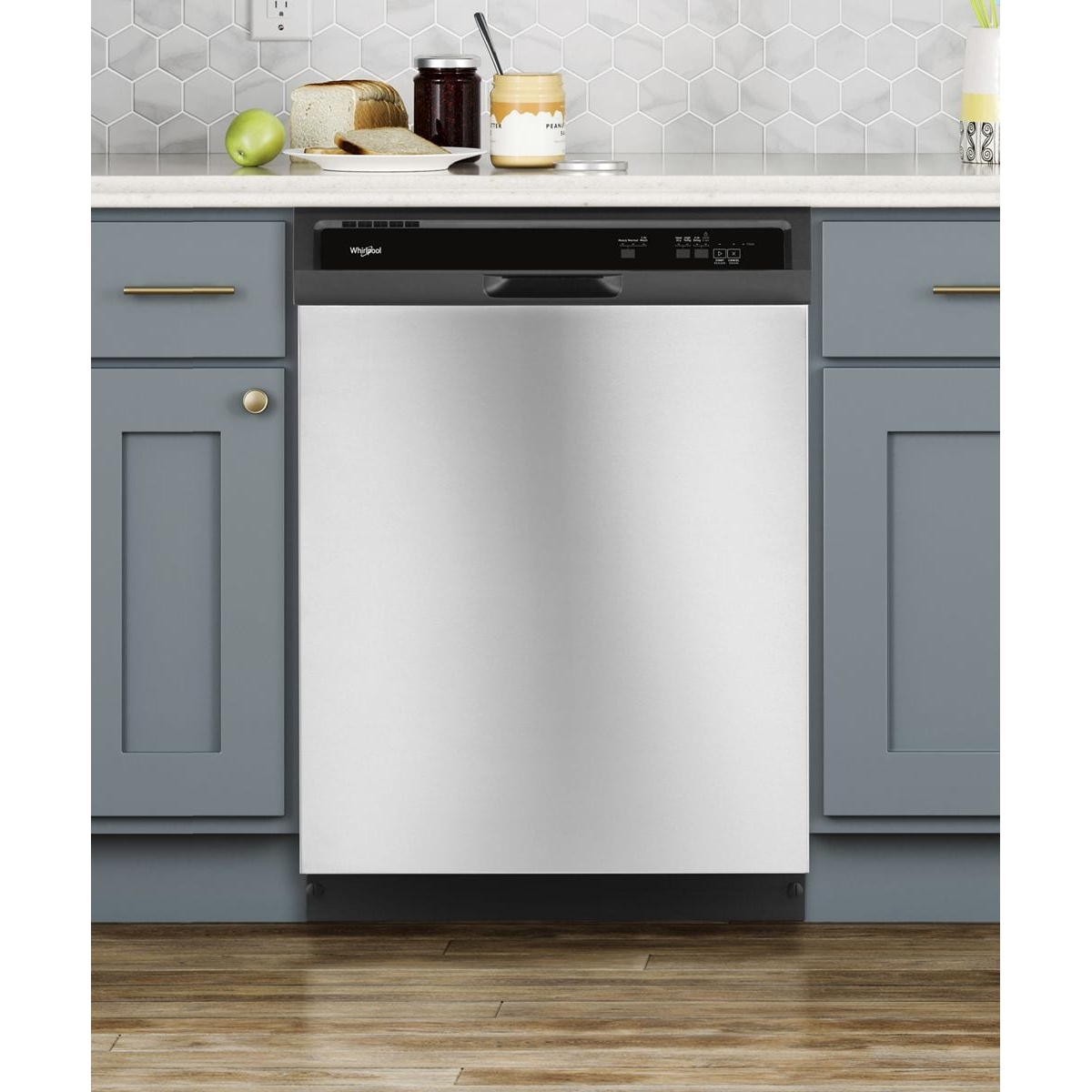 Whirlpool WDF330PAHS stainless steel dishwasher installed between blue-grey kitchen cabinets with gold hardware, shown in a styled kitchen setting