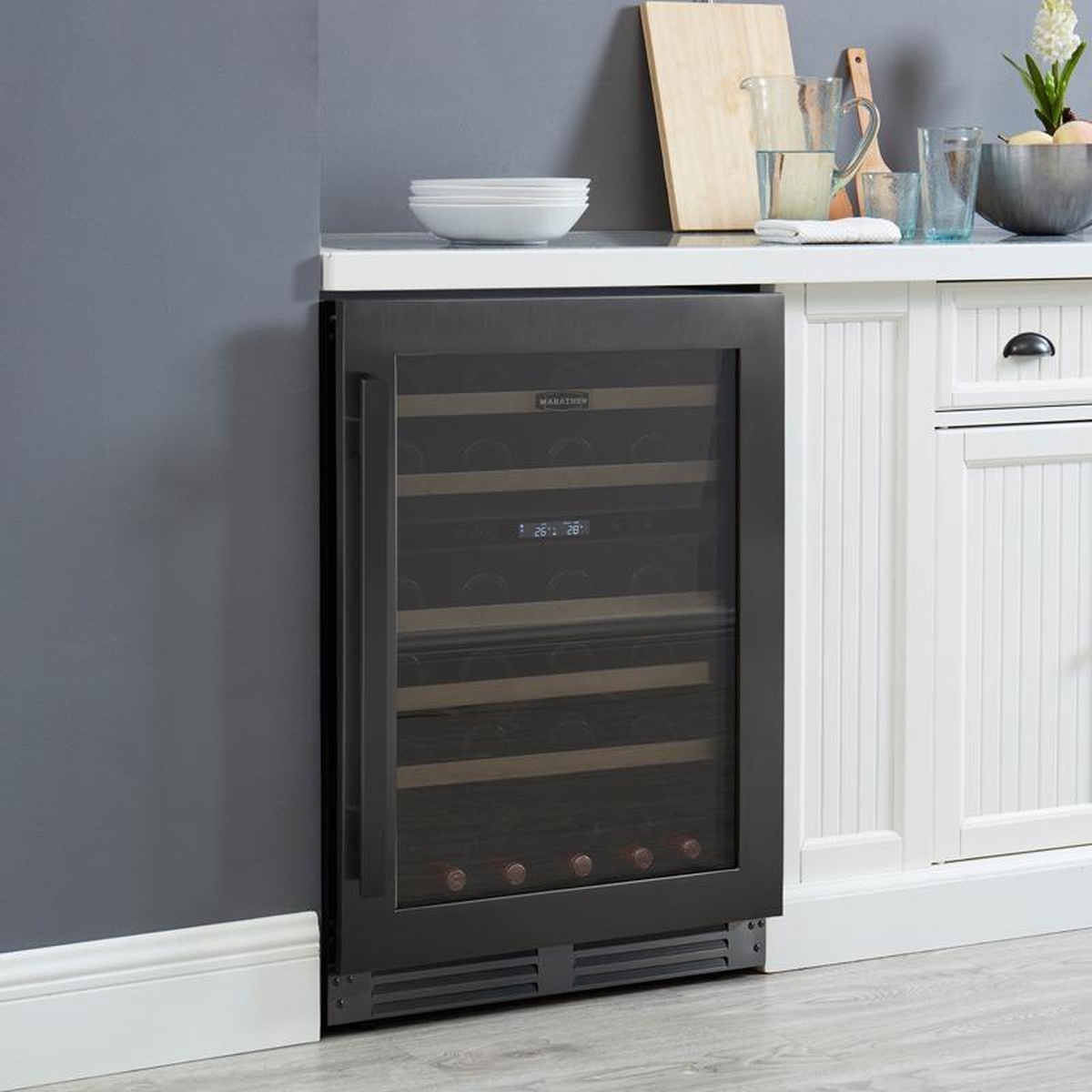 Marathon MWC56-DBLS wine cooler built into white kitchen cabinetry under a white countertop with kitchen accessories on top