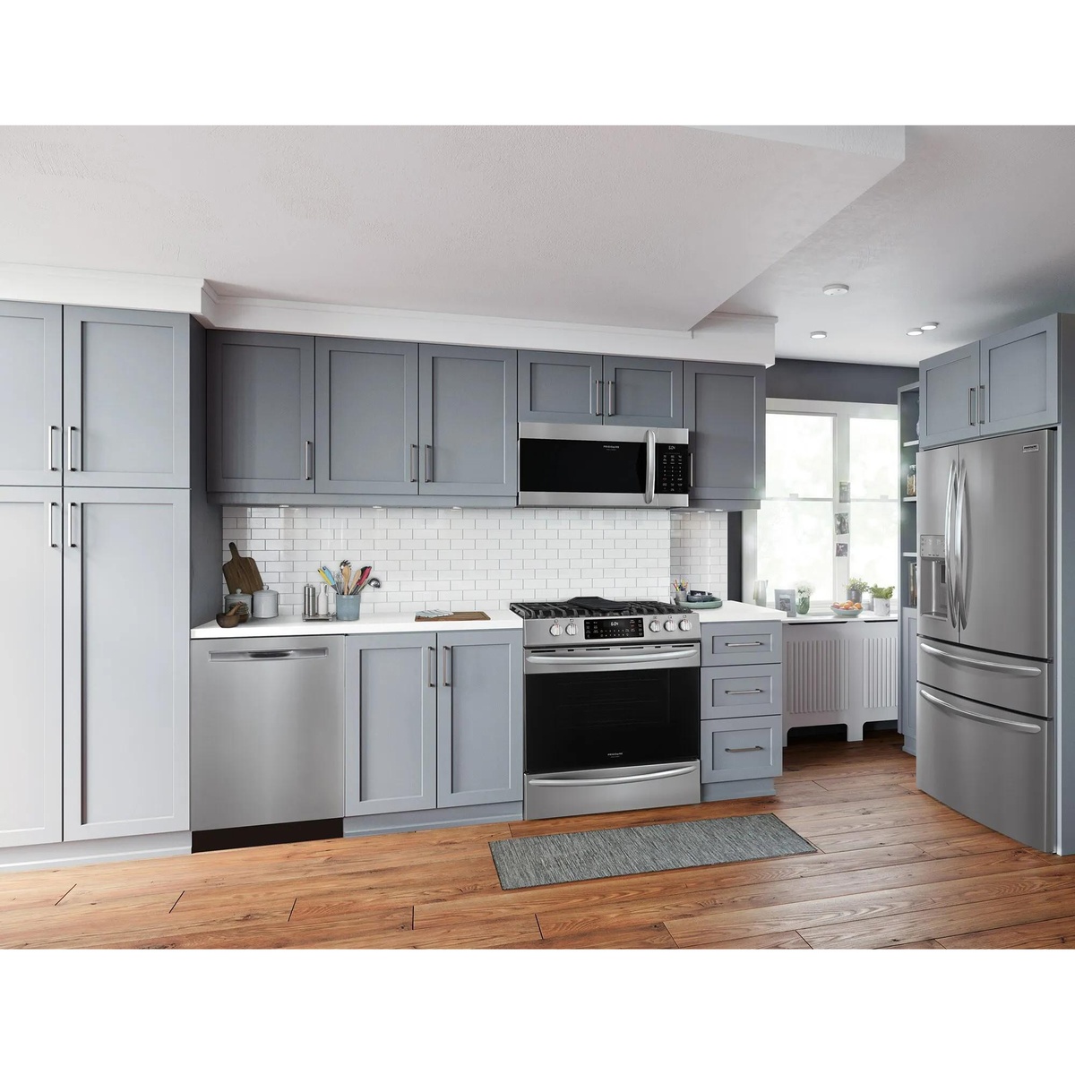 Frigidaire Gallery stainless steel range installed in a modern grey shaker-cabinet kitchen alongside matching dishwasher, over-the-range microwave, and French door refrigerator