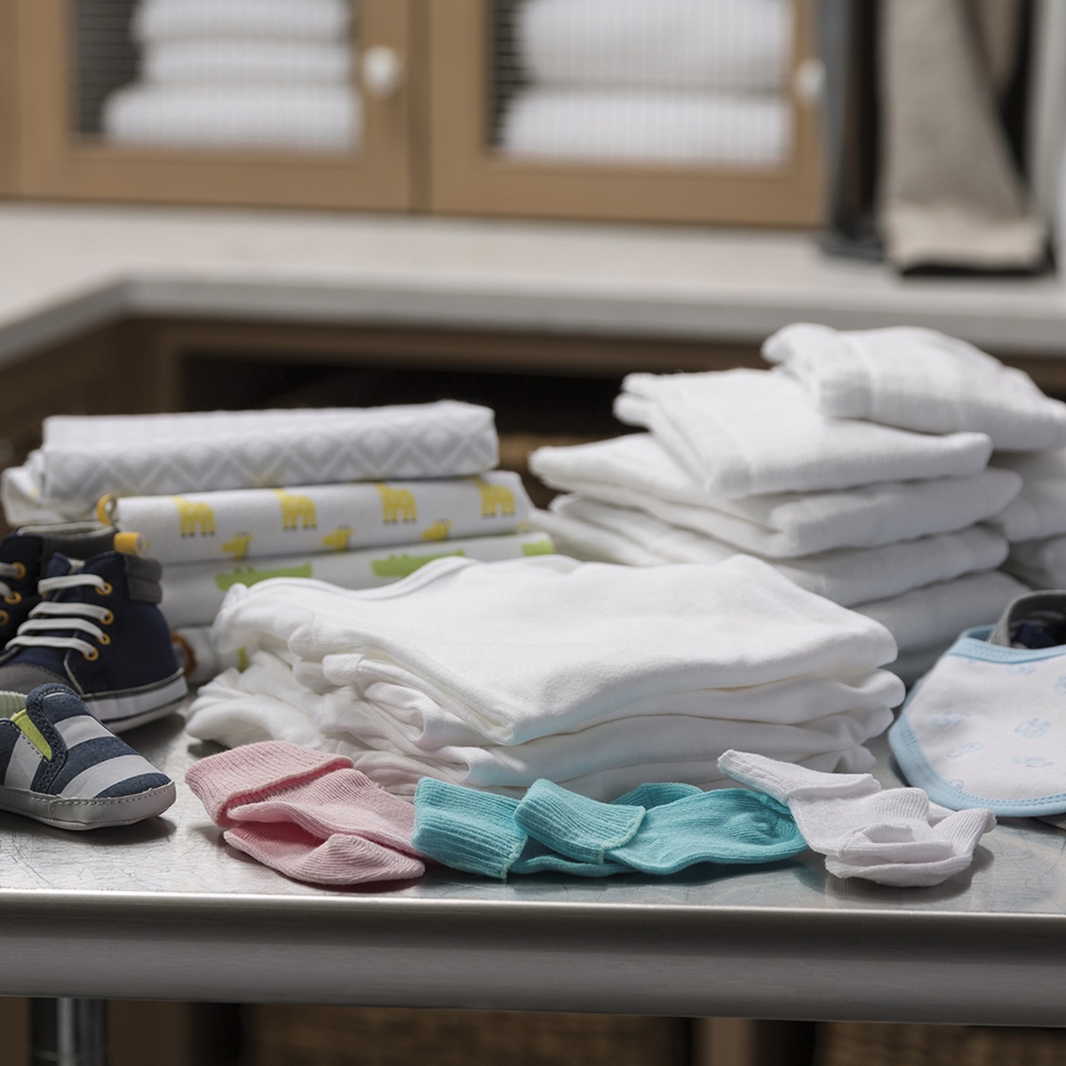 Folded baby clothes, socks and bibs arranged on a table to illustrate the SaniFresh cycle.